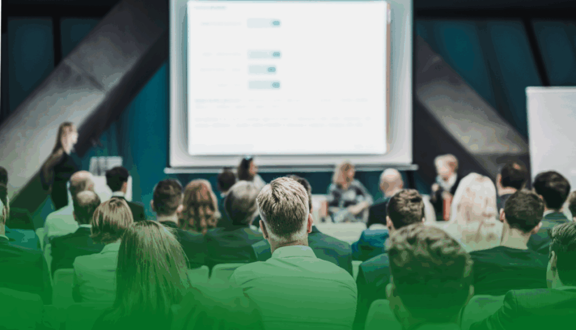 Personas asistiendo a una conferencia en un auditorio, con una ponente en el escenario y una pantalla de presentación proyectada al fondo. Personas asistiendo a una conferencia en un auditorio, con una ponente en el escenario y una pantalla de presentación proyectada al fondo.