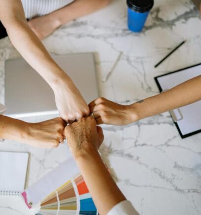 Cuatro manos de personas chocando los puños en señal de unión y trabajo en equipo